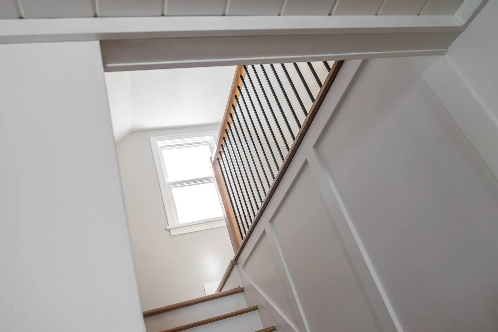 Staircase from below showing railing and shiplap ceiling